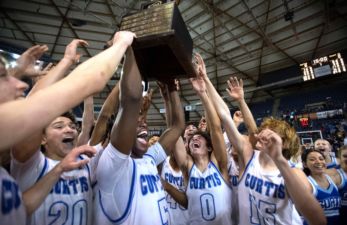 The Curtis Vikings hoist the state championship trophy after defeating top-ranked Mount Si, 52-49 in overtime of the WIAA 4A Boys Basketball State Championship game in the Tacoma Dome in Tacoma, Washington, on Saturday, March 5, 2022.