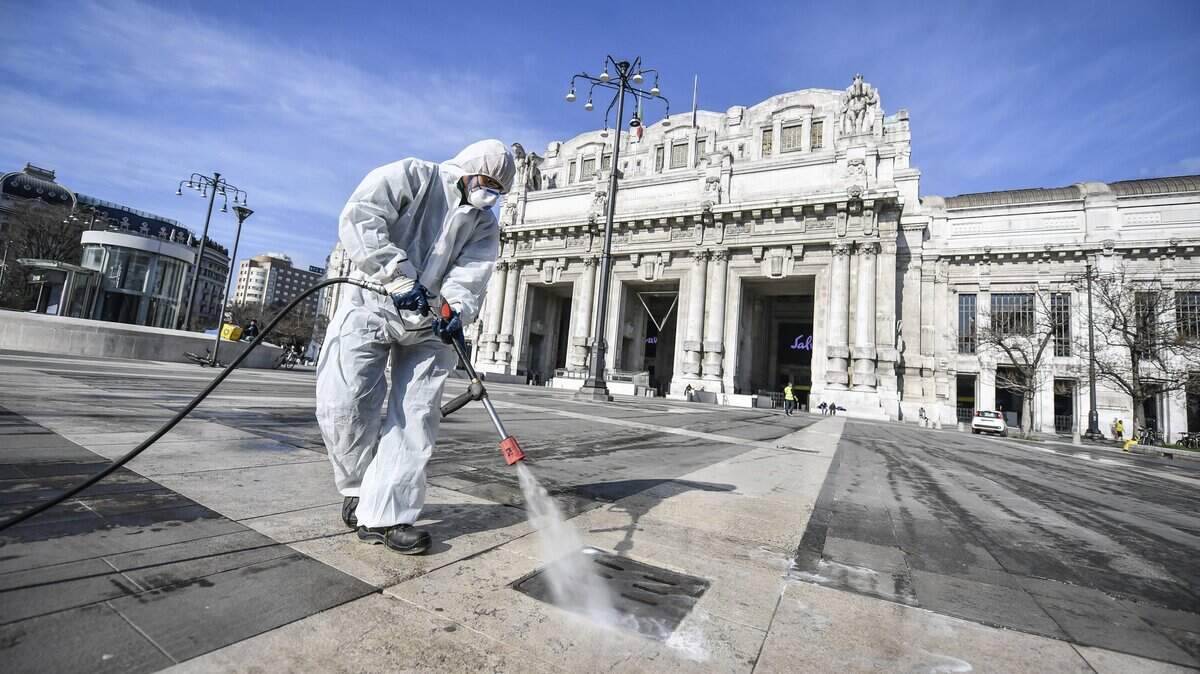 A worker wearing a protective suit disinfects the area in front of the Centrale main railway station, in Milan, Italy, Friday.