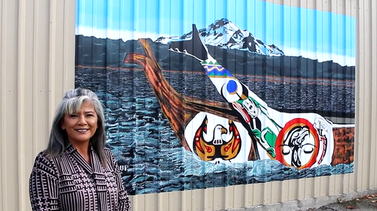 Lummi Nation artist Yolanda Felix-Wilbur discusses the meaning behind her piece depicting the Lummi Nation’s history, canoe journey and the tradition of the potlatch. It reads through symbolism on two canoes from right to left, she explained. The piece, now on display at Pioneer Park in Ferndale is one of two new murals representing the Lummi community and history as part of the city’s Downtown Mural Project.