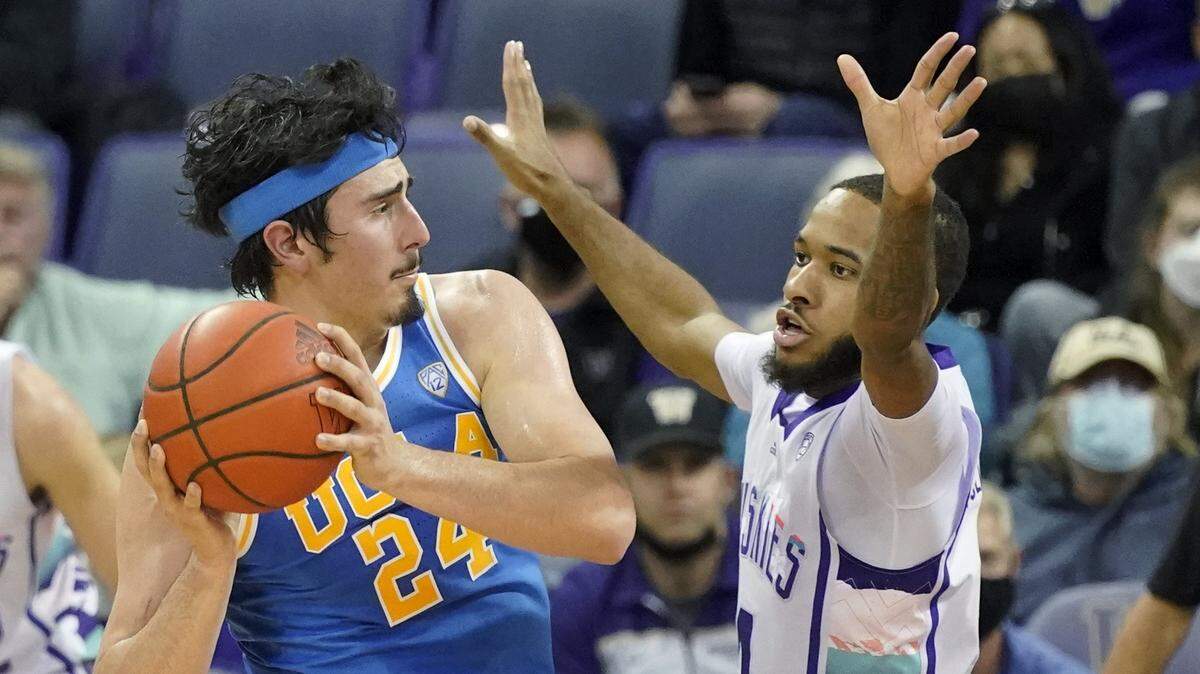 UCLA guard Jaime Jaquez Jr. (24) looks to pass around the defense of Washington guard PJ Fuller, right, during the first half of an NCAA college basketball game, Monday, Feb. 28, 2022, in Seattle. (AP Photo/Ted S. Warren)
