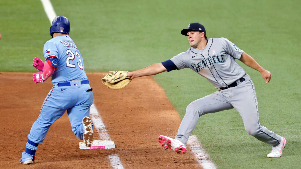 Texas Rangers catcher Jose Trevino (23) evades a tag by Seattle Mariners first baseman Evan White (12) as he makes it safely to first during the fifth inning of a baseball game Sunday, May 9, 2021, in Arlington, Texas. (AP Photo/Michael Ainsworth)