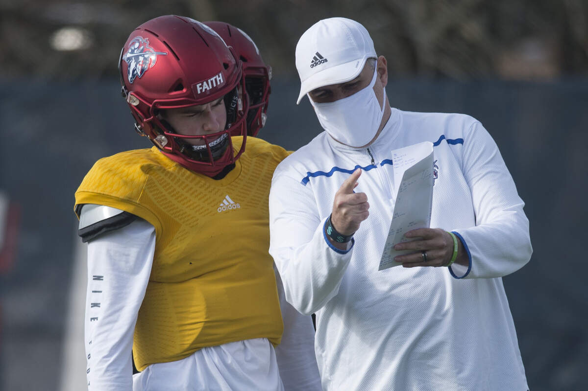 Kennedy Catholic High School quarterback Sam Huard and coach Sheldon Cross go over a play during practice on Tuesday, March 23, 2021 at Kennedy Catholic High School in Burien, Wash.