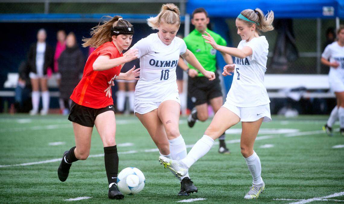 Olympia defender Lucy Clarke (10) and midfielder Emma Hays take the ball away from Camas forward Lily Loughney during Thursday evening’s District 3/4 girls soccer championship game at Ingersoll Stadium in Olympia, Washington, on Nov. 4, 2021. Camas won the game, 3-1.
