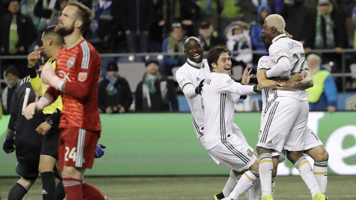 Seattle Sounders goalkeeper Stefan Frei, left, walks off the pitch as Portland Timbers’ Dairon Asprilla, right, is greeted by teammates, after Asprilla made a penalty kick during a shootout to give the Timbers the win in a second-leg MLS playoff soccer match, Thursday, Nov. 8, 2018, in Seattle. The Sounders beat the Timbers 3-2 in the match, giving the aggregate series a 4-4 tie, and the Timbers proceeded to win the series in a penalty kick shootout. (AP Photo/Ted S. Warren)