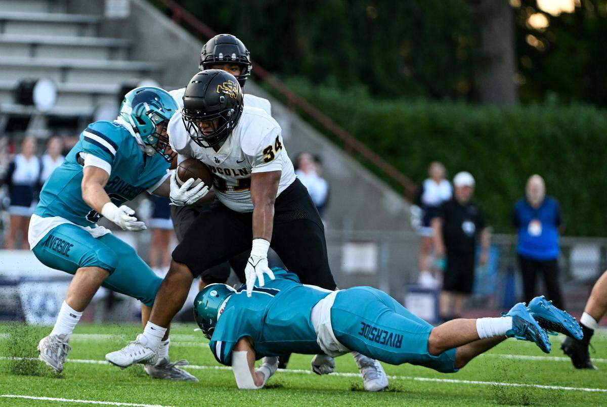 Lincoln’s Kelly Sio-Fetaui (34) runs through Auburn Riverside defenders during the first half of the high school football game at Auburn Memorial Stadium, Friday, Sept. 1, 2023, Auburn, Wash.