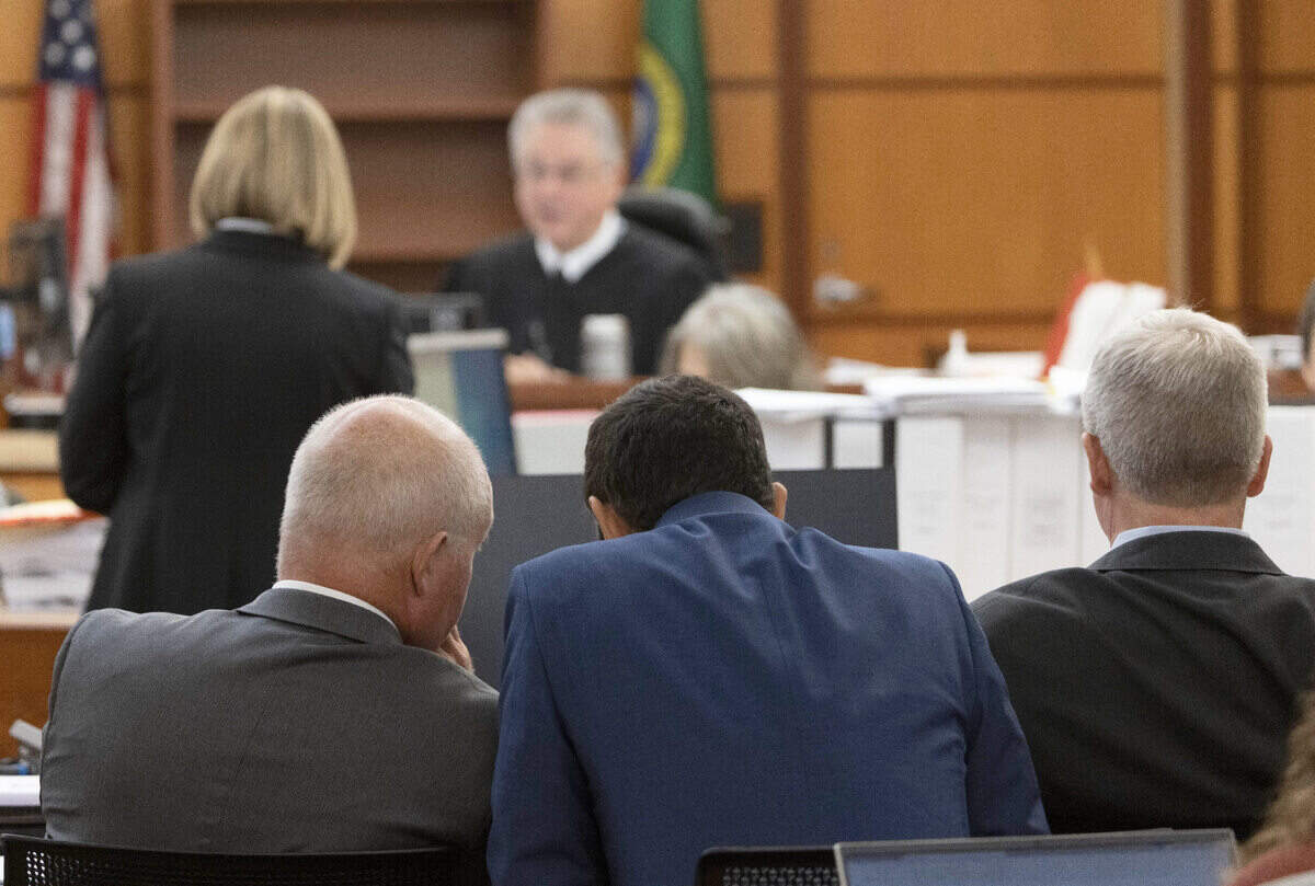 As prosecuting attorney Lori Nicolavo confers with Pierce County Superior Court Judge Bryan Chushcoff (in background) during the trial of Tacoma Police officers accused in the death of Manny Ellis held at Pierce County Superior Court, Wednesday Nov. 8, 2023, in Tacoma, Wash., defense attorney Brett Purtzer, left, speaks with Tacoma police officer Christopher Burbank. At right is defense attorney Wayne Fricke. Officers Christopher Burbank, Matthew Collins and Timothy Rankine are charged with his death. (Ellen M. Banner / Pool / The Seattle Times)