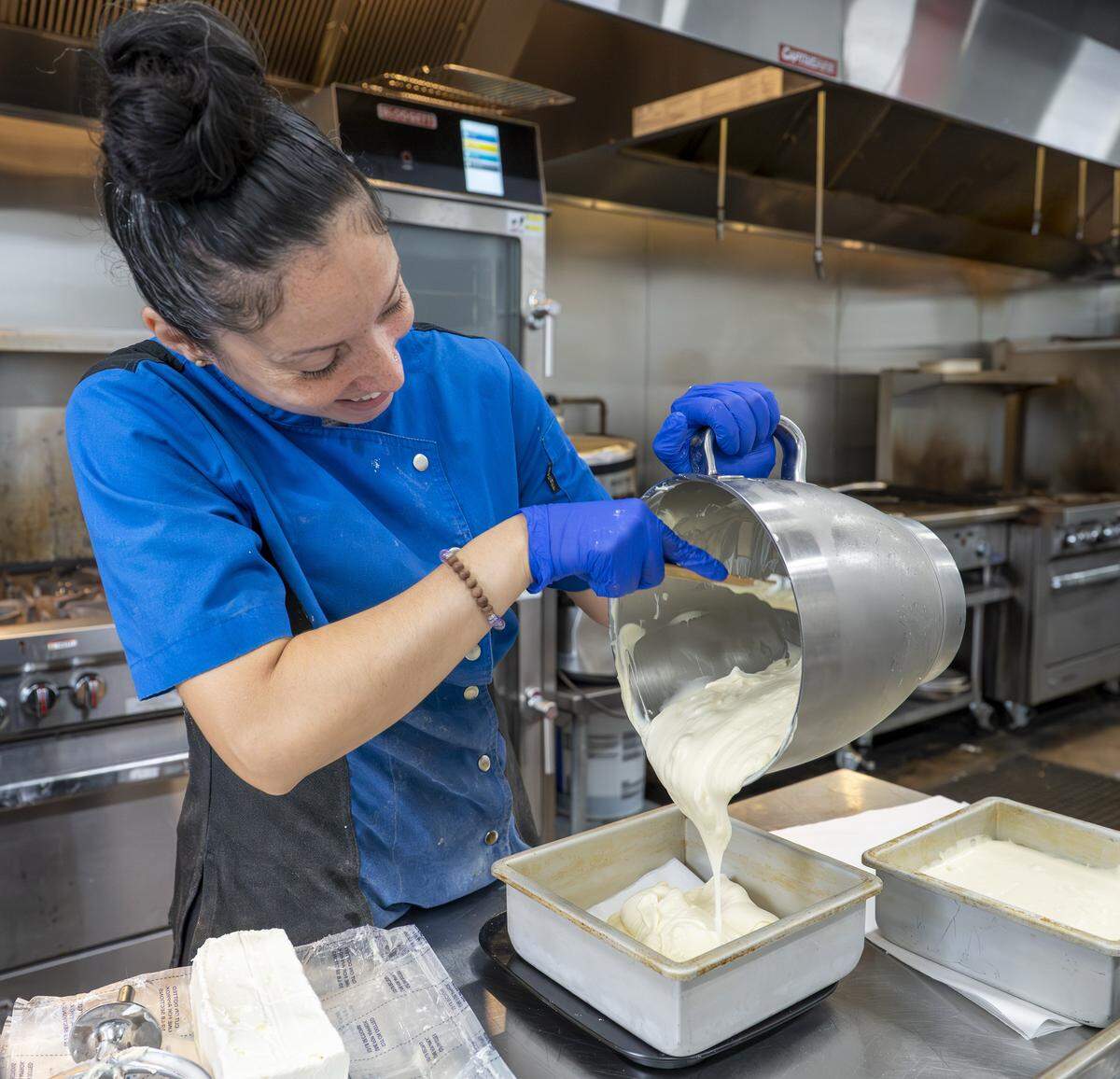 Lydia Mendez, owner of Little Miss Sweets NYC, pours the base of a classic New York-style cheesecake into a pan on Wednesday, Aug. 6, 2025, in Tacoma, Wash.