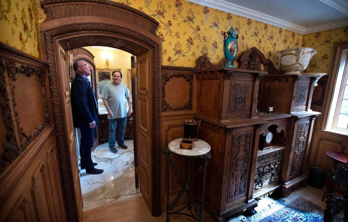 Realtor Mike Larson (left) gets a look at the Thornewood Carriage House in Lakewood, Washington, from owner Jonn Mason on Tuesday, April 19, 2022. The room features padded silk-covered walls and imported carved wood panels and doorways from the 1600s.