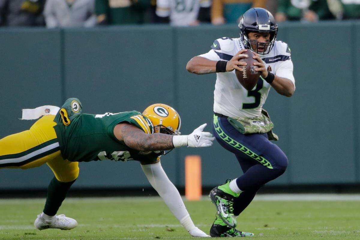 Seattle Seahawks’ Russell Wilson gets away from Green Bay Packers’ Preston Smith during the first half of an NFL football game Sunday, Nov. 14, 2021, in Green Bay, Wis. (AP Photo/Aaron Gash)