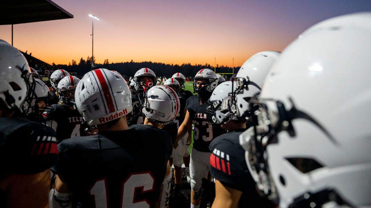 The sun sets southwest of the stadium as Yelm players huddle up prior to the start of a 3A SSC game against Timberline on Thursday, Oct. 13, 2022, at Yelm High School in Yelm, Wash.