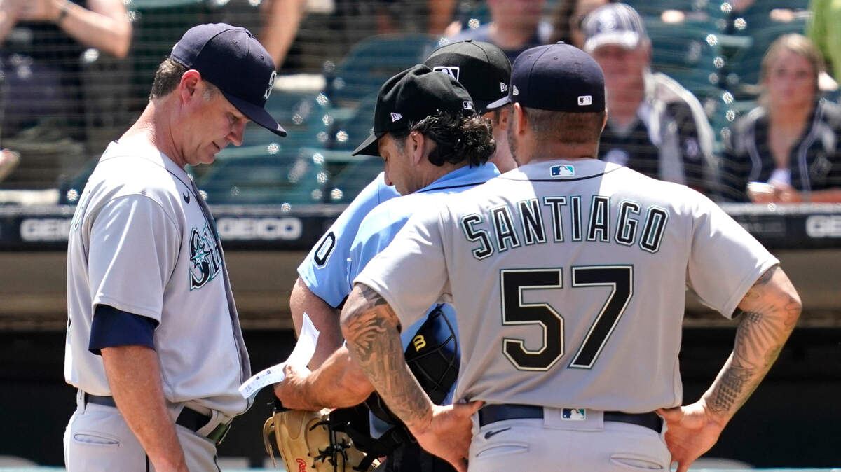 Seattle Mariners manager Scott Servais, left, listens to home plate umpire Phil Cuzzi about relief pitcher Hector Santiago, right, during the fifth inning in the first baseball game of a doubleheader against the Chicago White Sox in Chicago, Sunday, June 27, 2021. (AP Photo/Nam Y. Huh)