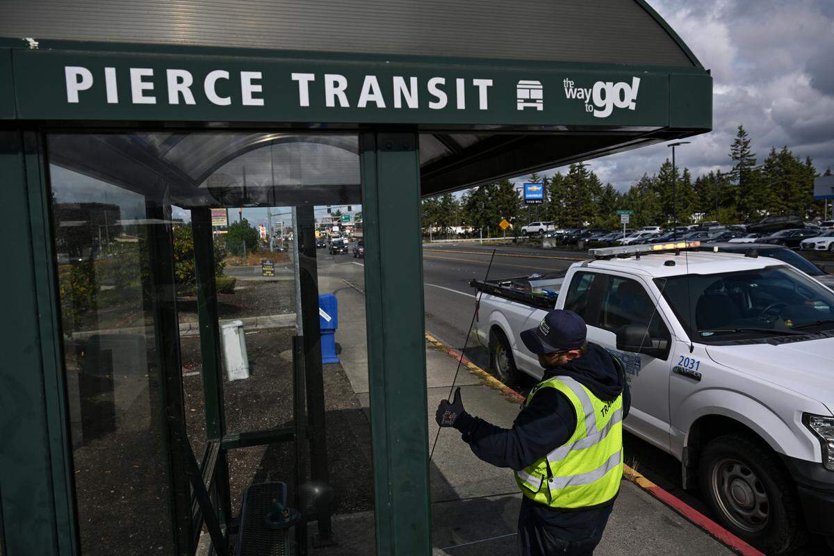 Kris Delano, transit facility specialist, replaces a broken pane of glass at a vandalized bus shelter on Pacific Avenue South, Wednesday, Sept. 20, 2023, in Tacoma.