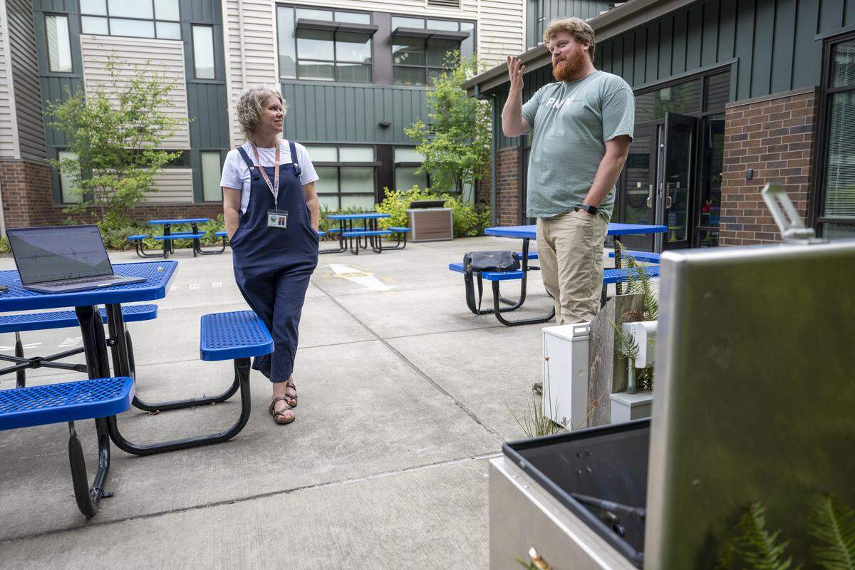 Tehaleh Heights Elementary principal Jennifer Knight, left, speaks with Doug Gibbons, a field technician and seismology lab coordinator for the Pacific Northwest Seismic Network, near the organization’s urban station located in the elementary’s courtyard, front, on Thursday, Sept. 11, 2025, in Bonney Lake.