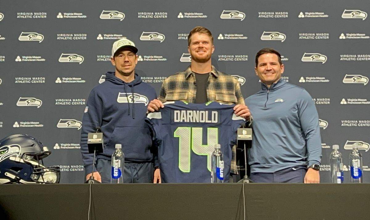 The Seahawks’ new number 14, Sam Darnold, after the 27-year-old quarterback last of the Minnesota Vikings signed his three-year, free-agent contract at Seattle’s team headquarters in Renton March 13, 2025. At left is Seahawks offensive coordinator Klint Kubiak. At right is coach Mike Macdonald.