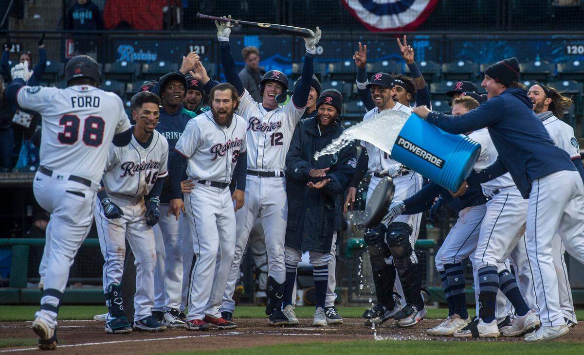 Tacoma Rainiers designated hitter Mike Ford (38) is greeted by teammates at the plate after hitting a walk-off solo home run against the Salt Lake Bees in the second game of a doubleheader on Saturday, April 9, 2022 at Cheney Stadium in Tacoma, Wash. The Rainiers won, 1-0.