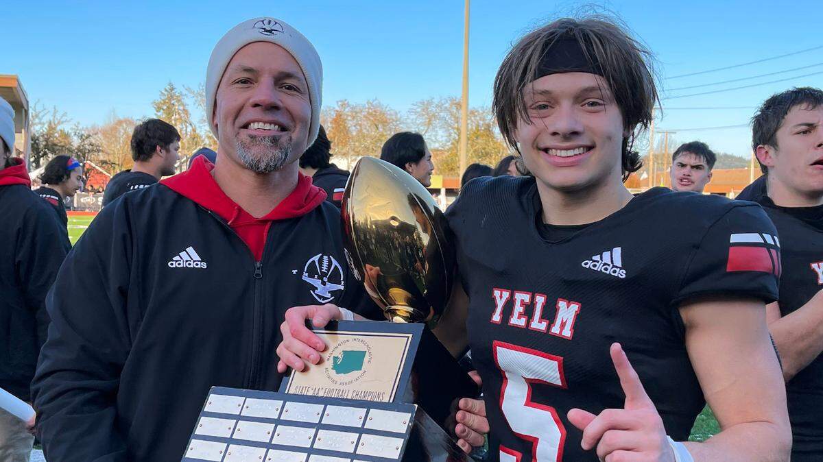 Yelm High School football coach Jason Ronquillo and wide receiver Kyler Ronquillo lift the Class 3A state championship trophy following their 20-13 title game win over Eastside Catholic on Saturday, Dec. 3, 2022 at Sparks Stadium in Puyallup, Wash.