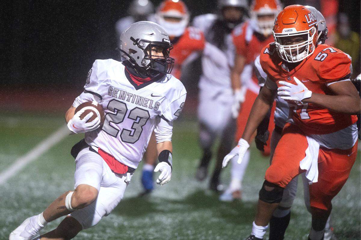 Spanaway Lake running back Jasiah Wagoner turns the corner on Lakes defensive lineman Kelvin Squires during Wednesday night’s high school football game at Harry Lang Stadium in Lakewood, Washington, on March 24, 2021.