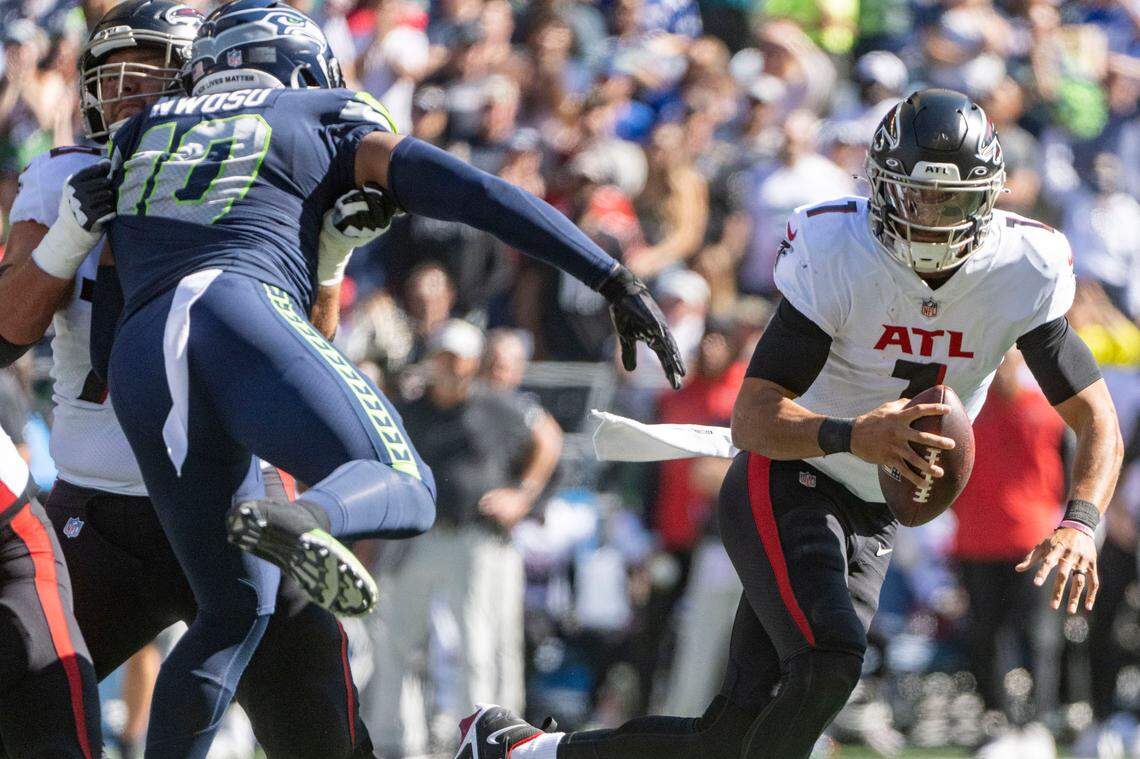 Atlanta Falcons quarterback Marcus Mariota (1) scrambles out of the pocket as Seattle Seahawks linebacker Uchenna Nwosu (10) rushes in during the first quarter of an NFL game on Sunday, Sept. 25, 2022, at Lumen Field in Seattle.