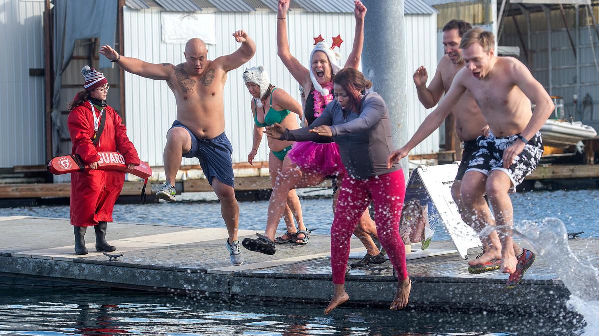FILE: A group of hardy souls make an exuberant leap off a dock during the Polar Bear Plunge Monday, Jan. 1, 2020, at the Point Defiance Marina boat launch. Dozens of participants braved the cold waters, saying the annual event is a way to cleanse the soul, usher in a new year and, in this instance, a new decade.