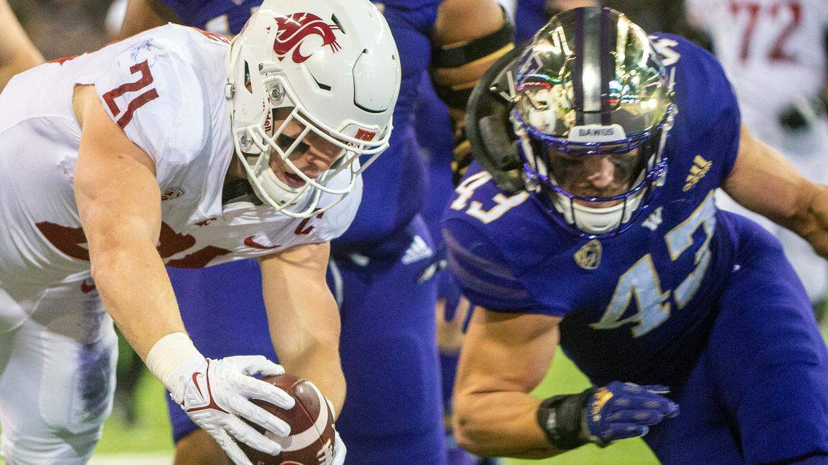 Washington State running back Max Borghi (21) dives into he endzone for a rushing touchdown as Washington linebacker Jackson Sirmon (43) attempts to knock him out of bounds during the first quarter of a Pac-12 game on Friday evening at Husky Stadium in Seattle.