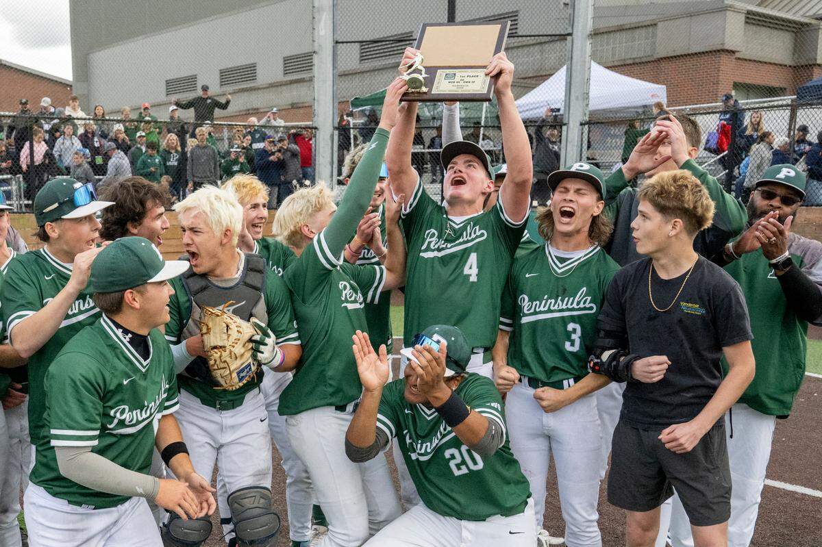 Peninsula players raise their 3A District Championship trophy in celebration of their win over Gig Harbor on Saturday, May 17, 2025, in Auburn, Wash.