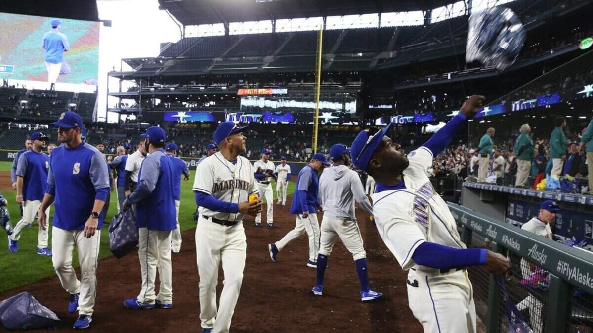 Guillermo Heredia, right, and other Mariners throw stuff to fans after defeating Texas at the M’s final game of the season, Sunday, Sept. 30, 2018, in Seattle. (Ken Lambert / The Seattle Times)