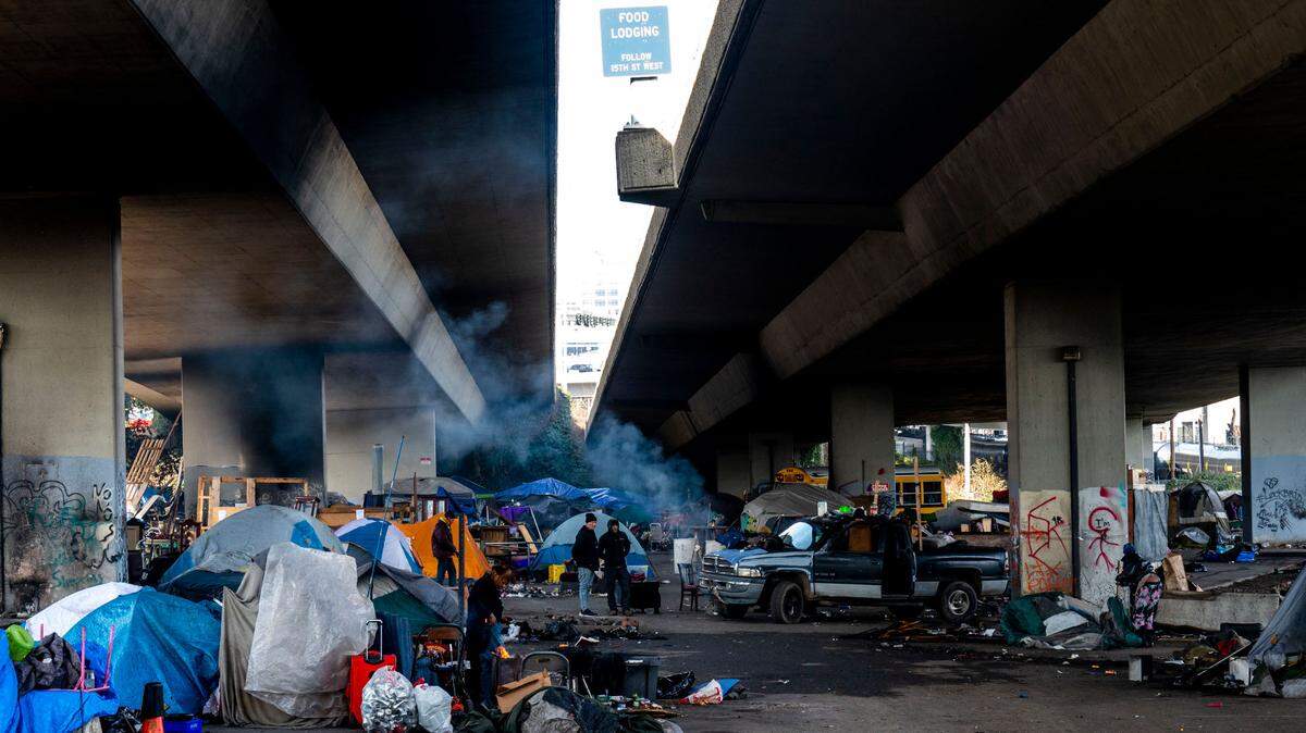 People begin to cleaning up their belongings at a homeless encampment underneath Interstate 705 along Puyallup Avenue on Friday, Jan. 28, 2022, in Tacoma, Washington.