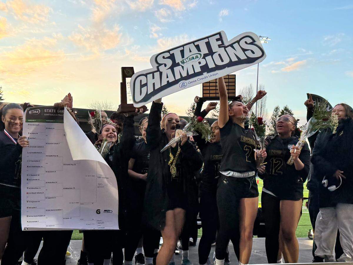 No. 1 Lincoln’s girls flag football team hoists the state championship trophy after beating No. 10 Seattle Prep, 21-14, in the 3A title game at Federal Way Memorial Field on Feb. 14, 2026, in Federal Way, Wash.