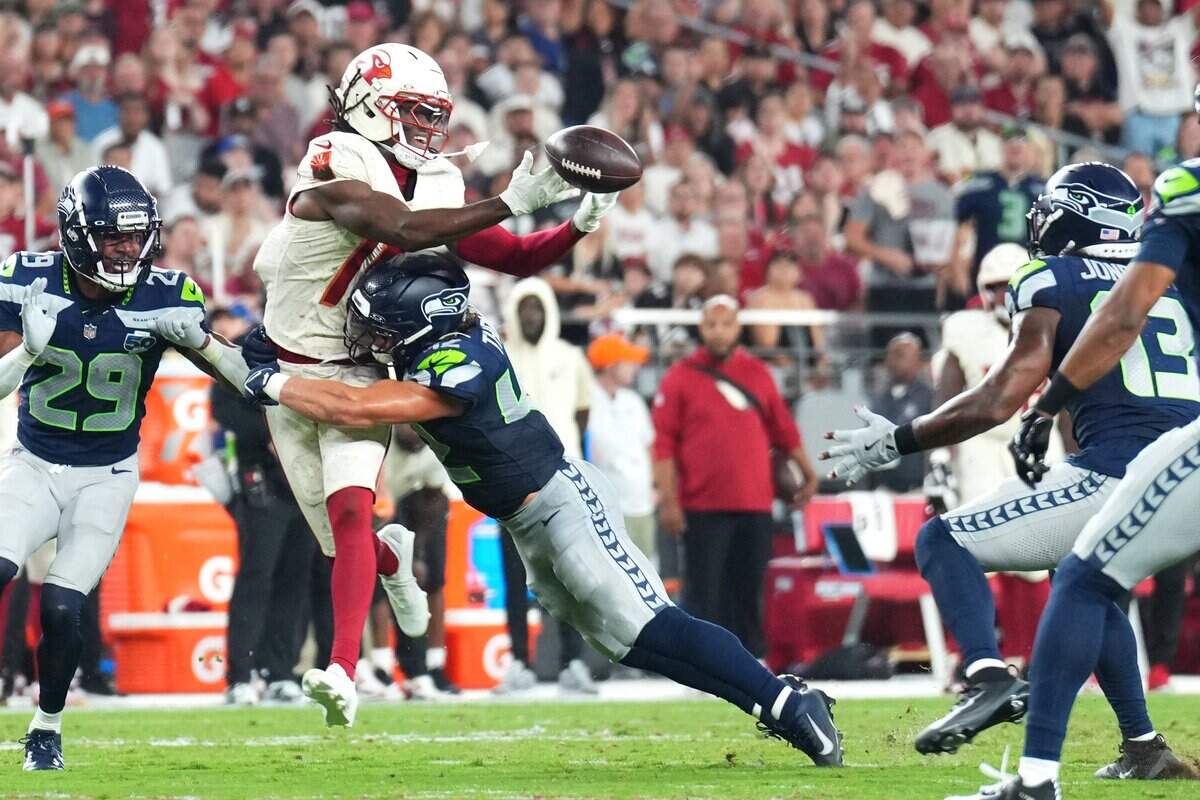 Arizona Cardinals wide receiver Marvin Harrison Jr. (18) cannot make a catch against Seattle Seahawks linebacker Drake Thomas (42) as linebacker Ernest Jones IV (13) intercepts the ball in the second quarter at State Farm Stadium. Mandatory Credit: Joe Camporeale-Imagn Images