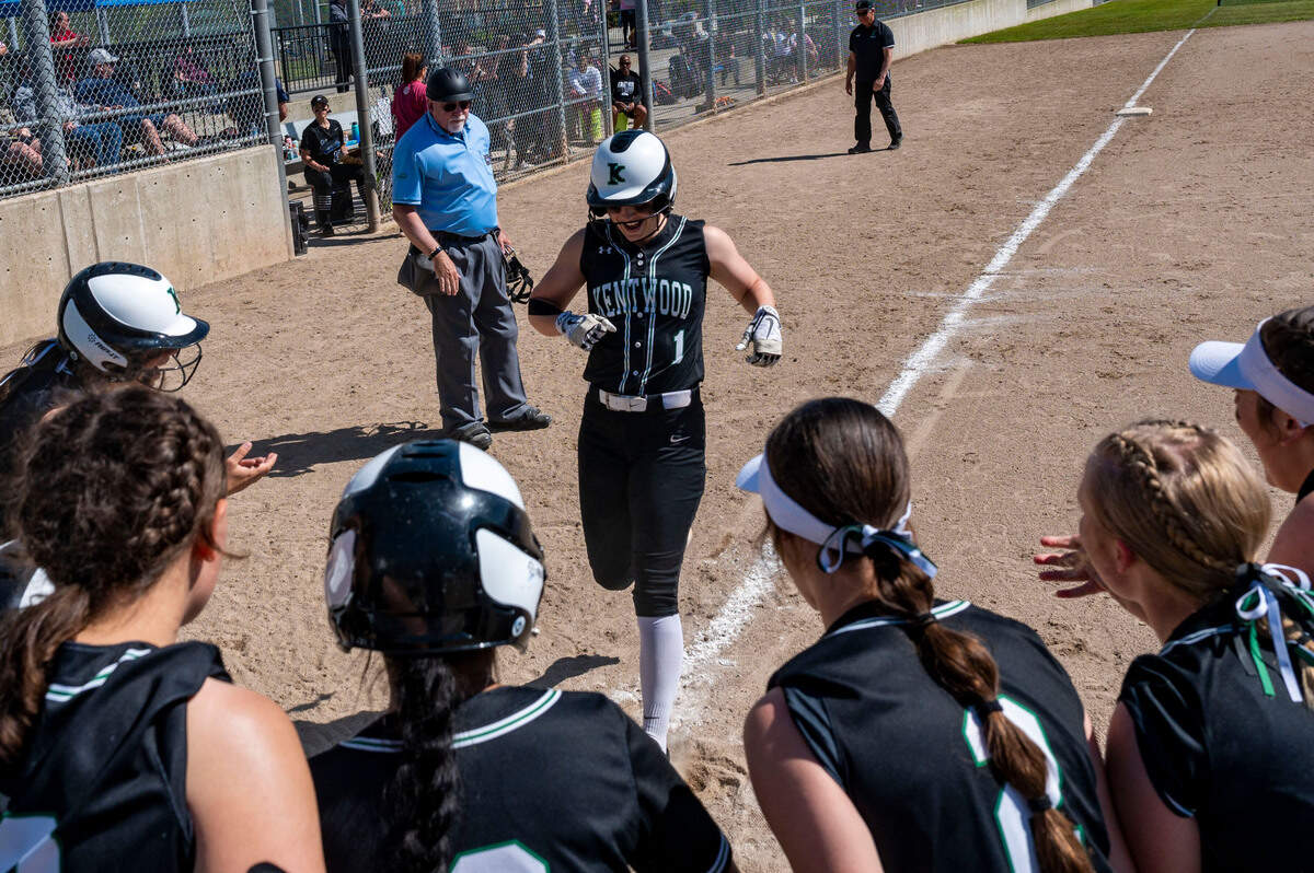 Kentwood players surround home plate to greet Sarah Wright after her home run in the bottom of the fifth inning of the District 2/3 tournament championship game against Skyview on Saturday, May 21, 2022, at Kent Service Fields in Kent, Wash.