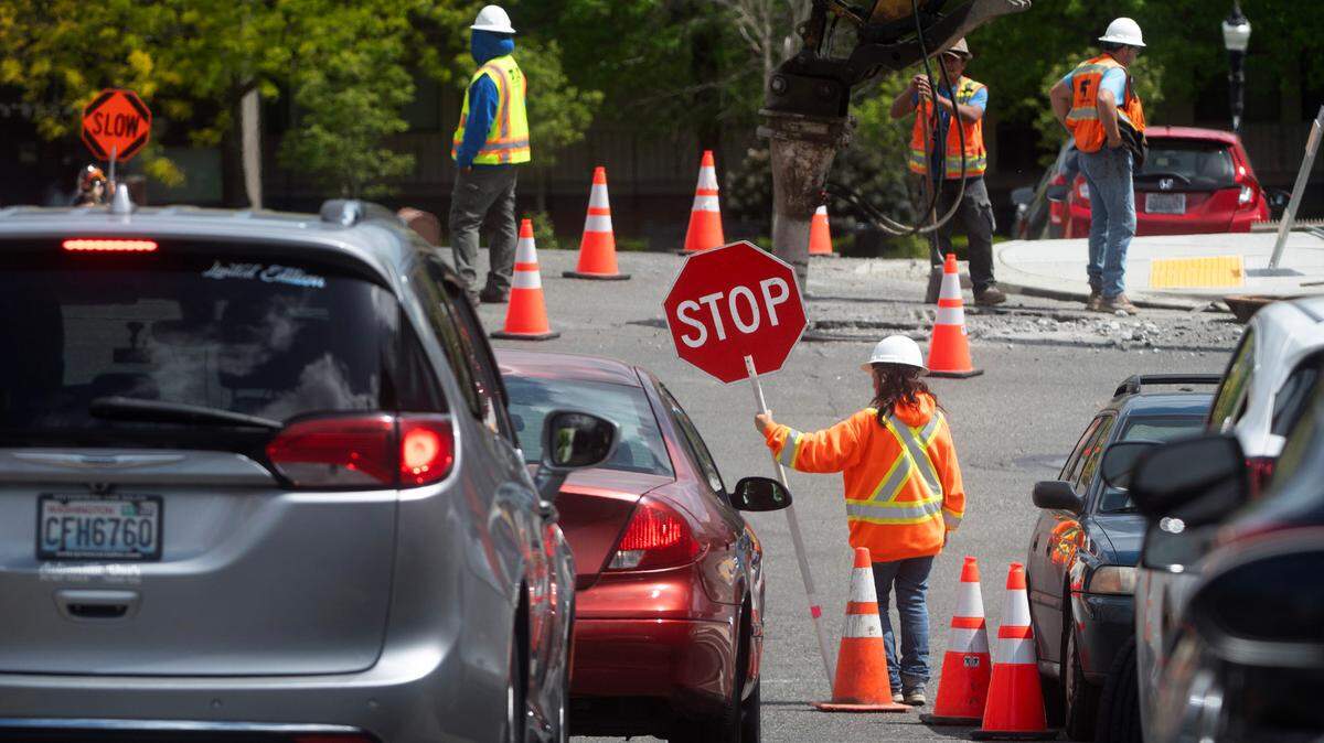 A work-zone flagger helps control traffic around a construction project at 6th Avenue and St. Helens Avenue in downtown Tacoma, Washington, on Thursday, May 16, 2024.