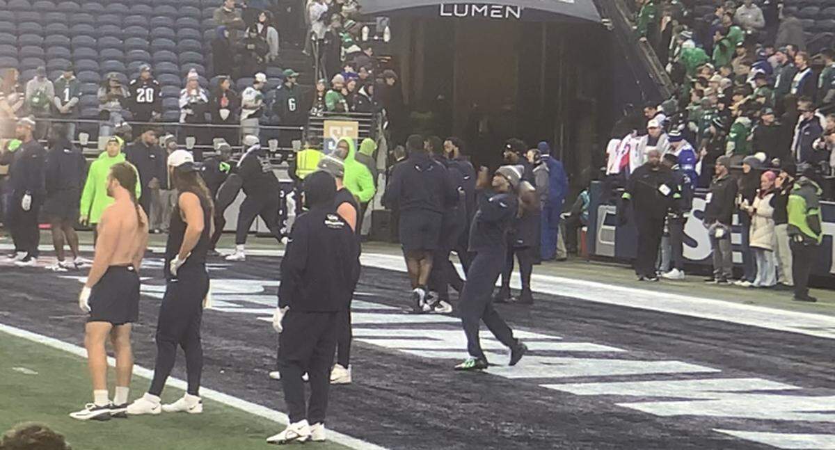 Geno Smith (in stocking cap) throws from the end zone testing his groin injury during early pregame work before the Seahawks played the Philadelphia Eagles at Lumen Field in Seattle Dec. 18, 2023.