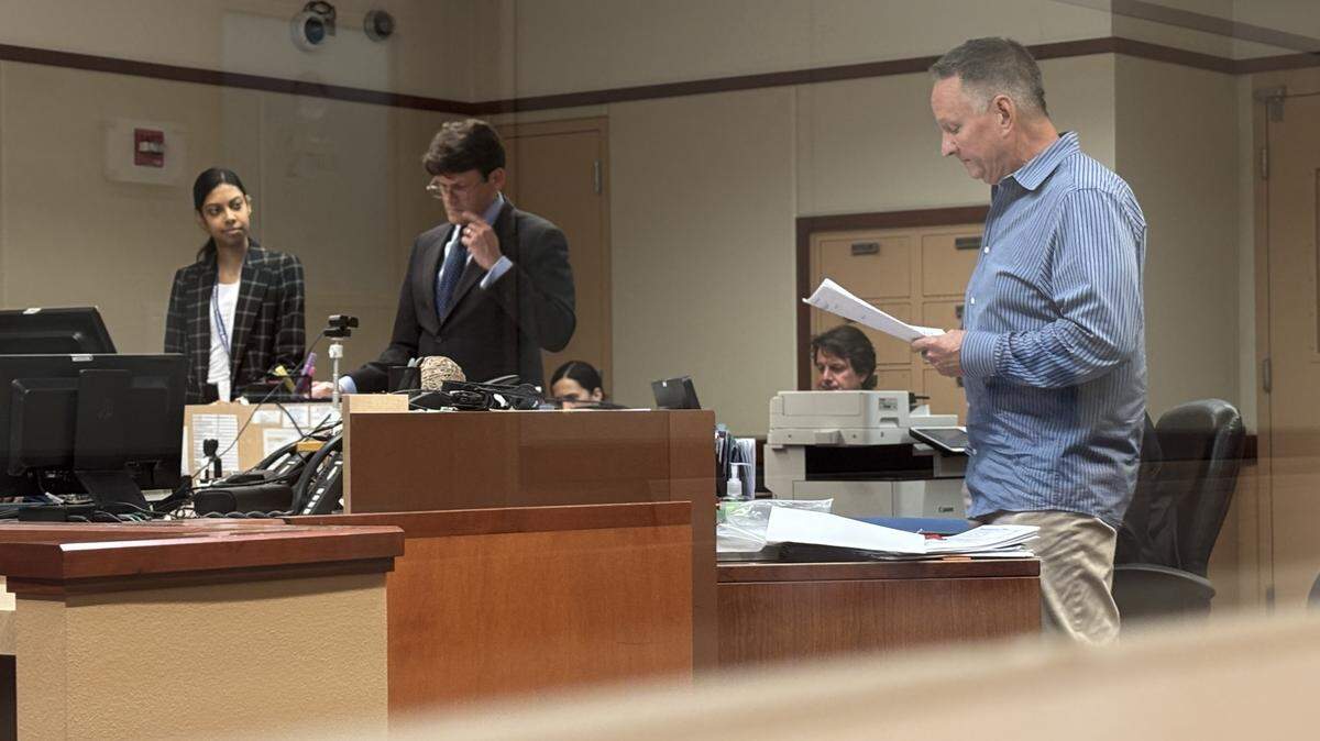Defendant Anthony Wayne Neely stands in front of a courtroom reading a written statement to the court next to his defense attorney. Behind him, the judicial assistant as well as Deputy Processing Attorney Matthew N. Thomas are standing and listening.