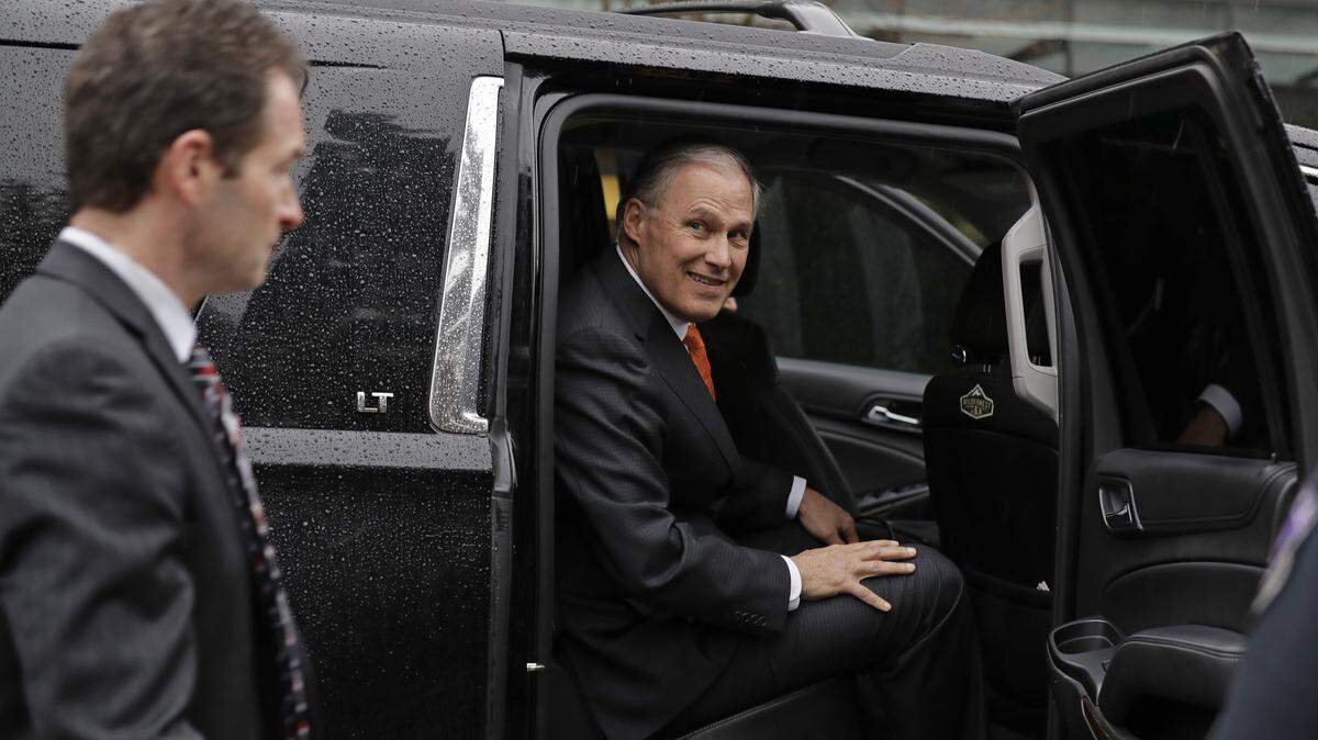 Washington Gov. Jay Inslee gets into his official vehicle near a member of his security detail following a speaking engagement at the University of Washington in Seattle on March 6.