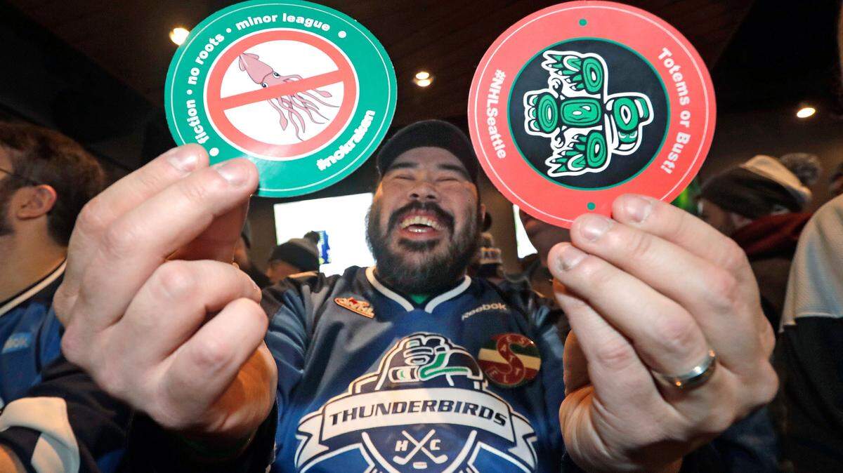 Otto Rogers playfully holds up stickers against the proposed name Kraken and in support of Totems following the announcement of a new NHL hockey team in Seattle, at a celebratory party Tuesday, Dec. 4, 2018, in Seattle. (AP Photo/Elaine Thompson)