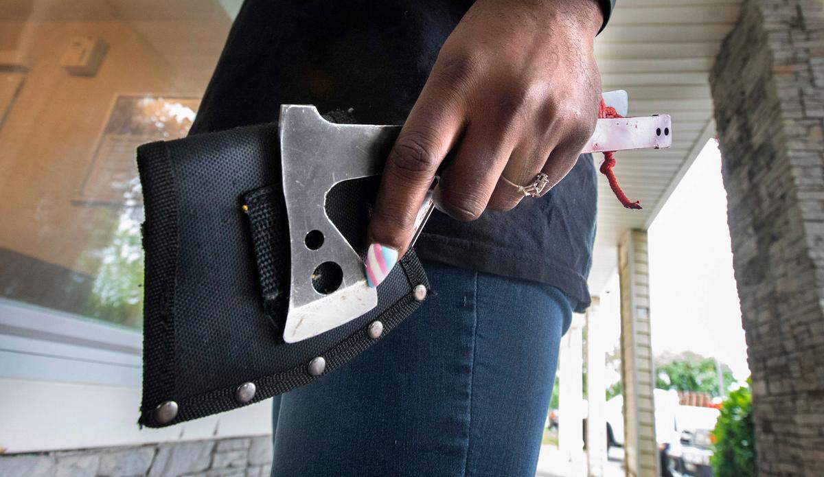 Janelle Wright carries a pair of hatchets on her hip while working her job as head housekeeper at the HomeTowne Studios hotel on Hosmer Street in Tacoma, Washington on July 8, 2022.