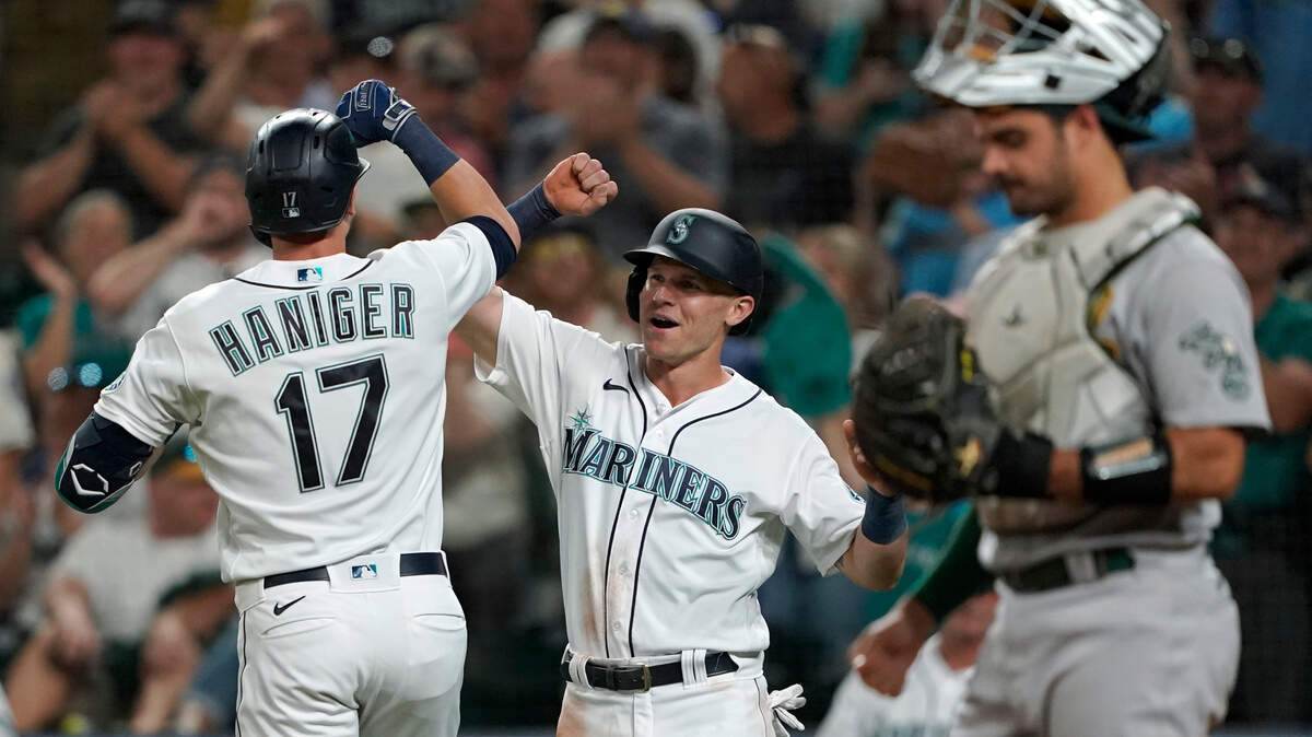 Seattle Mariners’ Mitch Haniger (17) is greeted by Jake Bauers, center, after Haniger hit a two-run home run to score Bauers against the Oakland Athletics during the fifth inning of a baseball game Saturday, July 24, 2021, in Seattle. (AP Photo/Ted S. Warren)