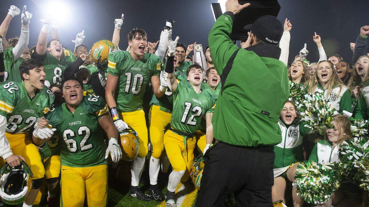 Tumwater players celebrate as athletic director Tim Graham presents the state championship trophy following the T-Birds’ 48-34 victory over the Steilacoom Sentinels during Saturday’s 2A football state championship game at Sparks Stadium in Puyallup on Dec. 7, 2019.