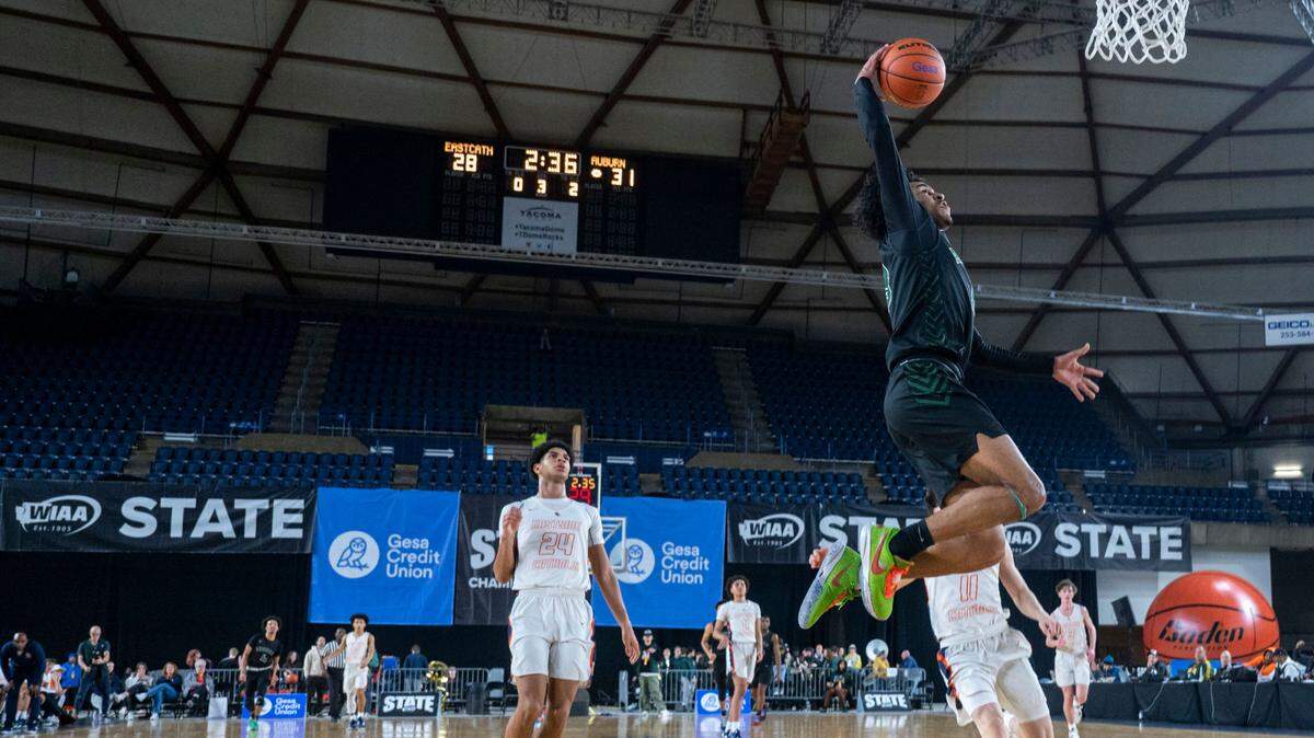 Auburn guard Tyrell Nichols (13) dunks the ball on a fast break as a pair of Eastside Catholic players jog back on defense during the third quarter of a Class 3A quarterfinal game on Thursday, March 2, 2023, in Tacoma, Wash.