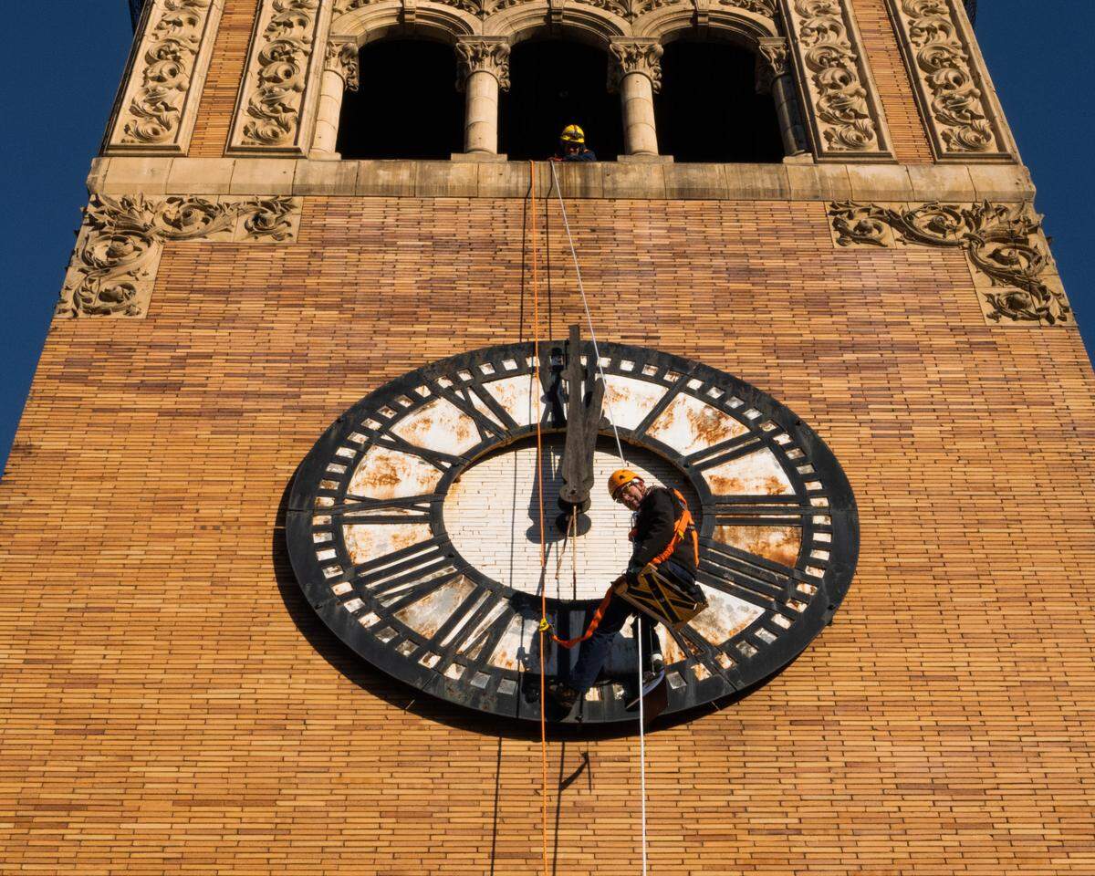A worker rappels down the clock face at Tacoma’s Old City Hall during recent repair work at the historic site. Old City Hall is set to reopen its first phase next summer.
