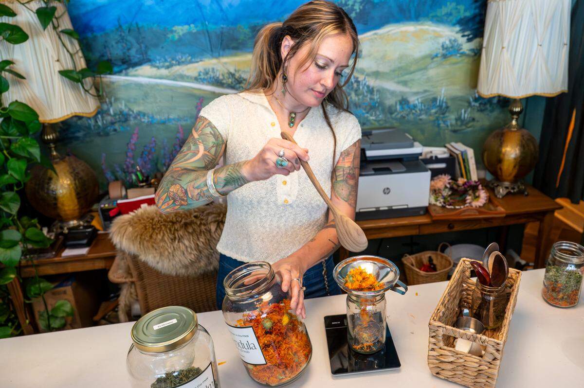 Rachele Piety measures out dried Calendula for an herbal infusion on Thursday, July 17, 2025, at Hawthorn & Honey in the Proctor neighborhood of Tacoma. Piety, a former apprentice of Hawthorn & Honey founder Sara Butters, also operates vintage shop Sassa Fratz out of the apothecary’s space.