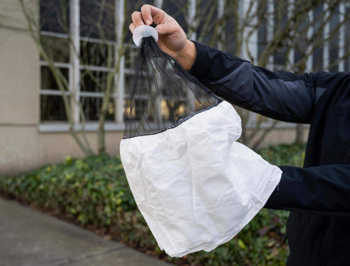 Sgt. Darren Moss holds a spit mask for demonstration outside the Pierce County Sheriff’s Department in Tacoma, Wash. on Friday, Feb. 11, 2022.