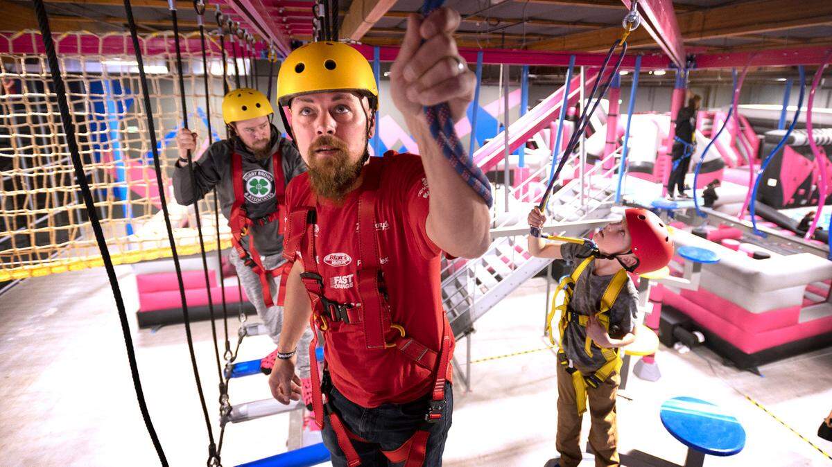 Ryan Campbell (from left), Kyle Brundage and his son, Brodi Brundage, all of Puyallup, navigate the Flying Leopard ropes course ten feet above the ground at Catapult Adventure Park in Puyallup, Washington, on Friday, Dec. 24, 2021.