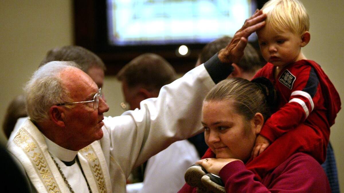 The Rev. Eugene Wiegman, left, blesses Jeremiah Rose, 1, as he sits on his mother, Hope Rose’s shoulders, during communion at the closing service at Luther Memorial Church in Tacoma in 2011.