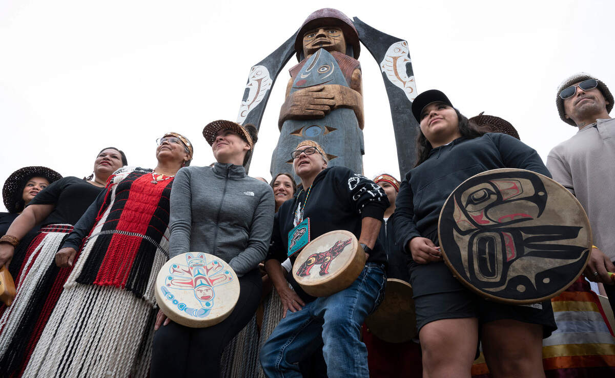 Puyallup tribal drummers gather for a photo beneath the new “Our Fisherman, Our Guardian” carved cedar following a dedication ceremony at Austin Park at txʷaalqəł Estuary on the waterfront in Gig Harbor, Washington, on Thursday, Sept. 15, 2022.