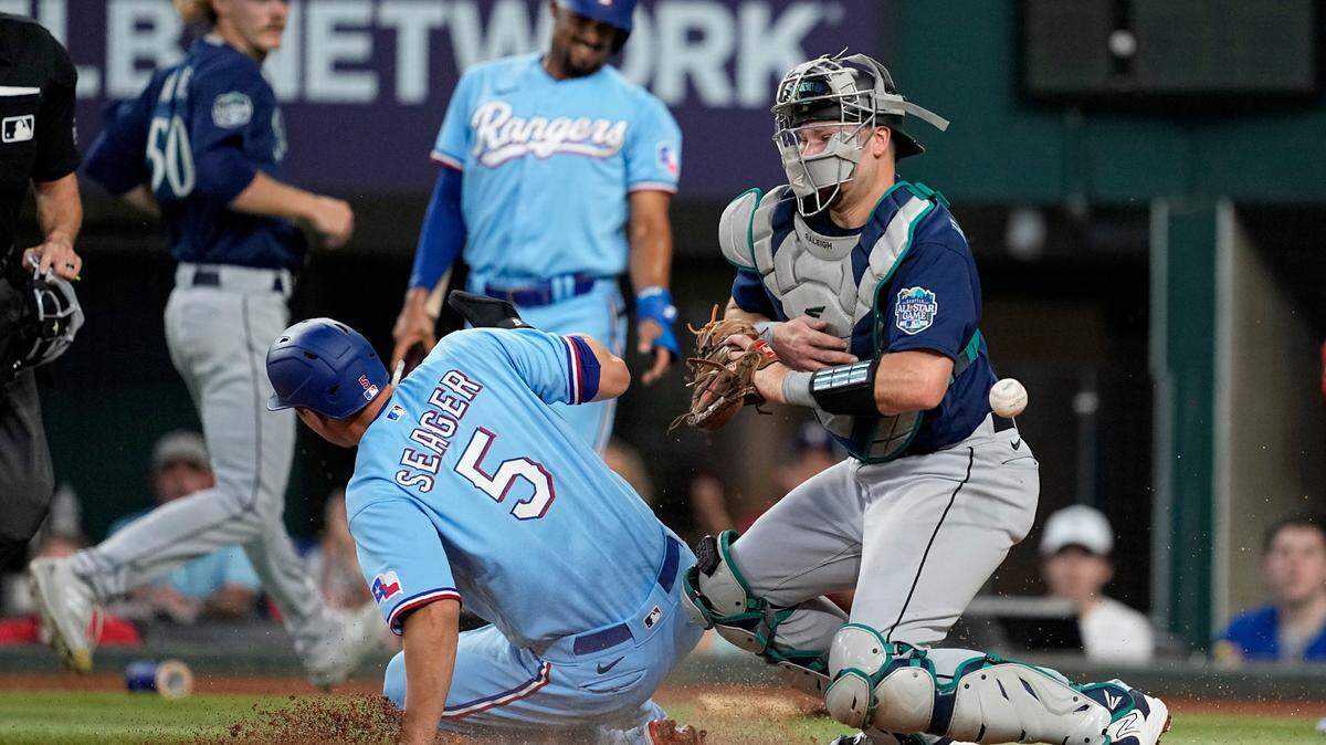Texas Rangers’ Corey Seager (5) scores on a Jonah Heim single as Seattle Mariners catcher Cal Raleigh, right, is unable to catch a throw to the plate in the first inning of a baseball game, Sunday, June 4, 2023, in Arlington, Texas. (AP Photo/Tony Gutierrez)