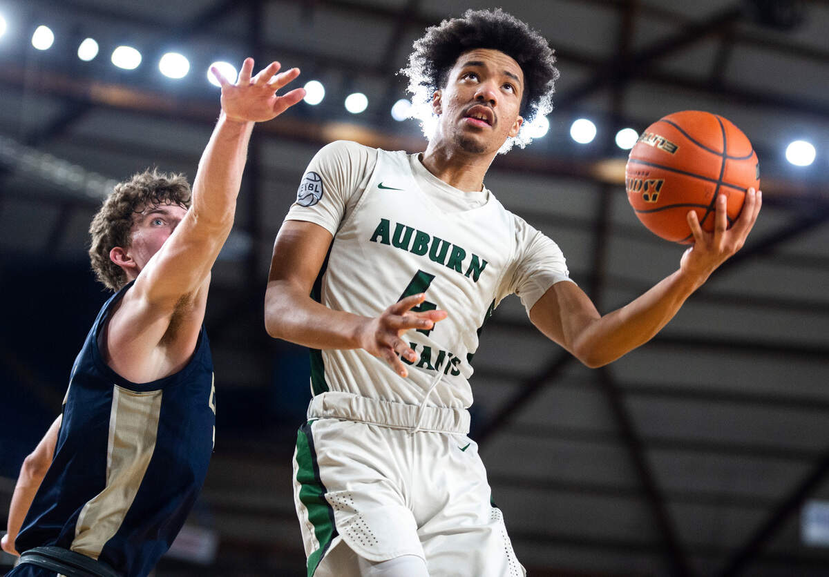 Auburn forward Semaj Brown (4) jumps to make an underhanded layup as Arlington forward David Zachman (14) tries to block him during an opening round game at the WIAA state basketball tournament in the Tacoma Dome in Tacoma, Washington, on Wednesday, March 1, 2023. Auburn won the game 52-41.