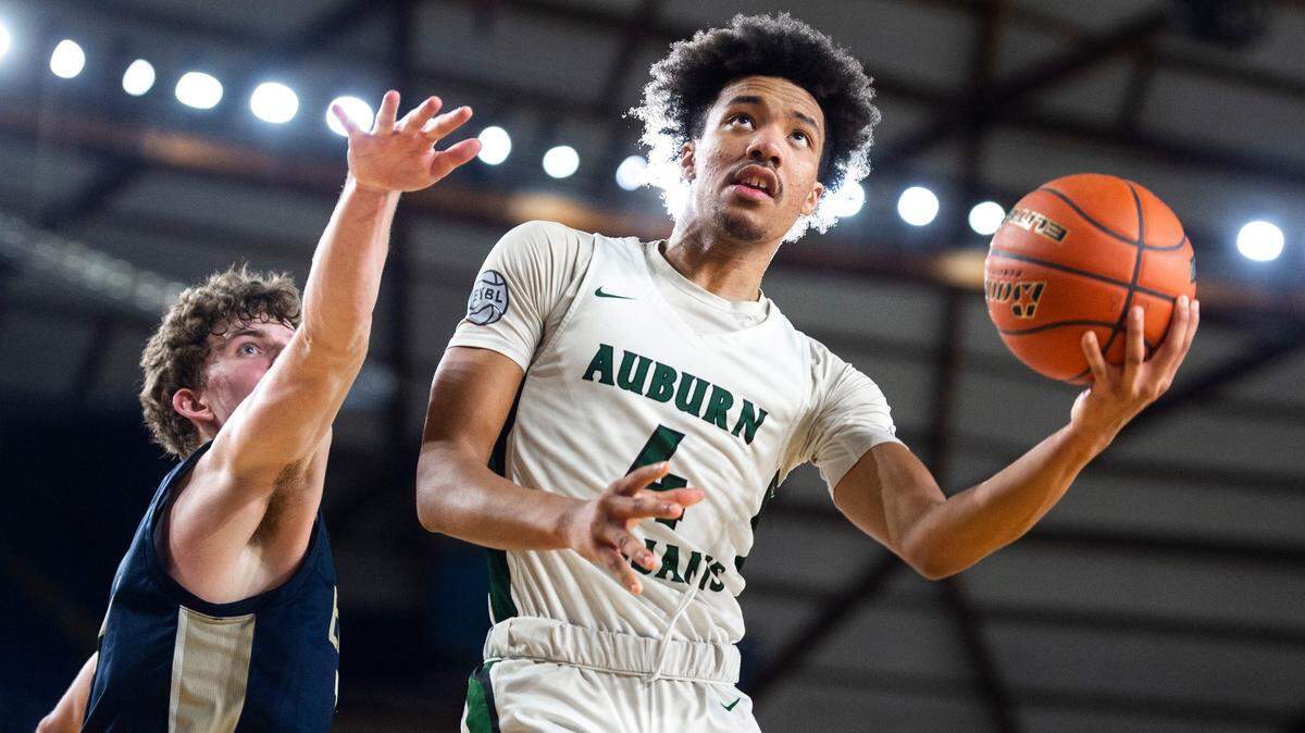 Auburn forward Semaj Brown (4) jumps to make an underhanded layup as Arlington forward David Zachman (14) tries to block him during an opening round game at the WIAA state basketball tournament in the Tacoma Dome in Tacoma, Washington, on Wednesday, March 1, 2023. Auburn won the game 52-41.