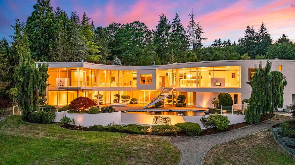 Lights gleam through floor-to-ceiling glass windows and doors of The S House on Wollochet Bay near Gig Harbor, Wash.