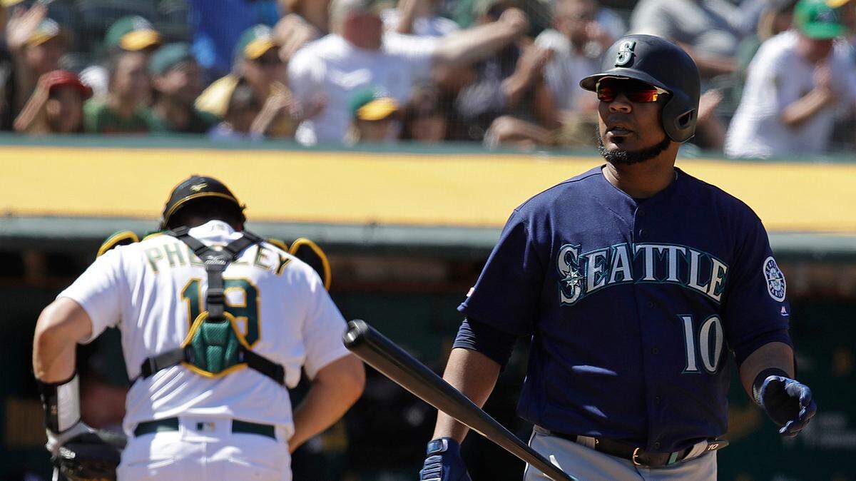 Seattle Mariners’ Edwin Encarnacion, right, tosses his bat after striking out to the Oakland Athletics in the eighth inning of a baseball game Saturday, May 25, 2019, in Oakland, Calif.